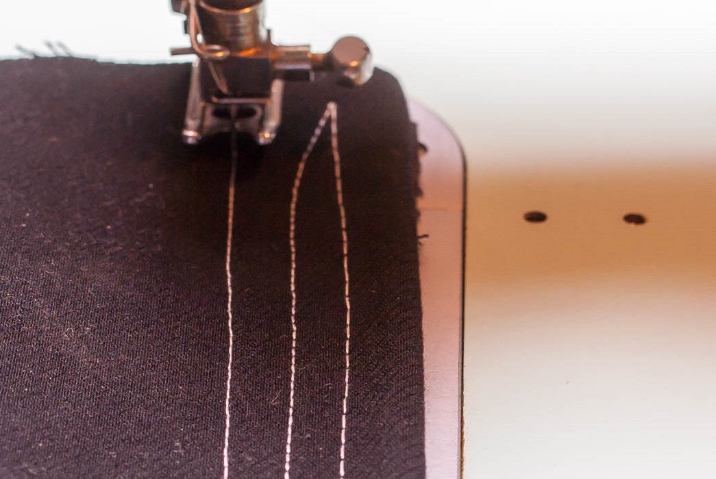 The tension on the leftmost stitch is too tight (you can tell by the bobbin thread poking up through the stitching). Compare this to the two lines of stitching with the correct tension.