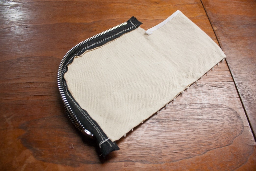 Running a stitch along the inside of the wallet to make a zip wallet.
